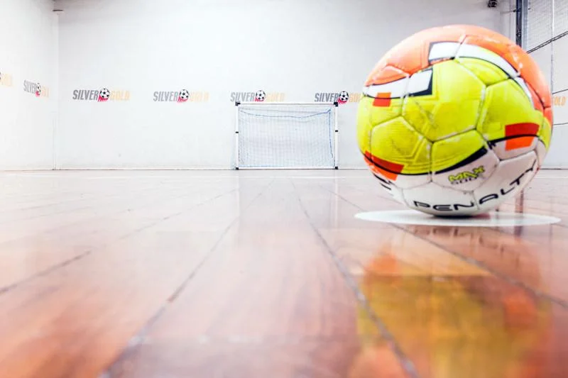 Bola de futsal sobre o piso de tacos da quadra